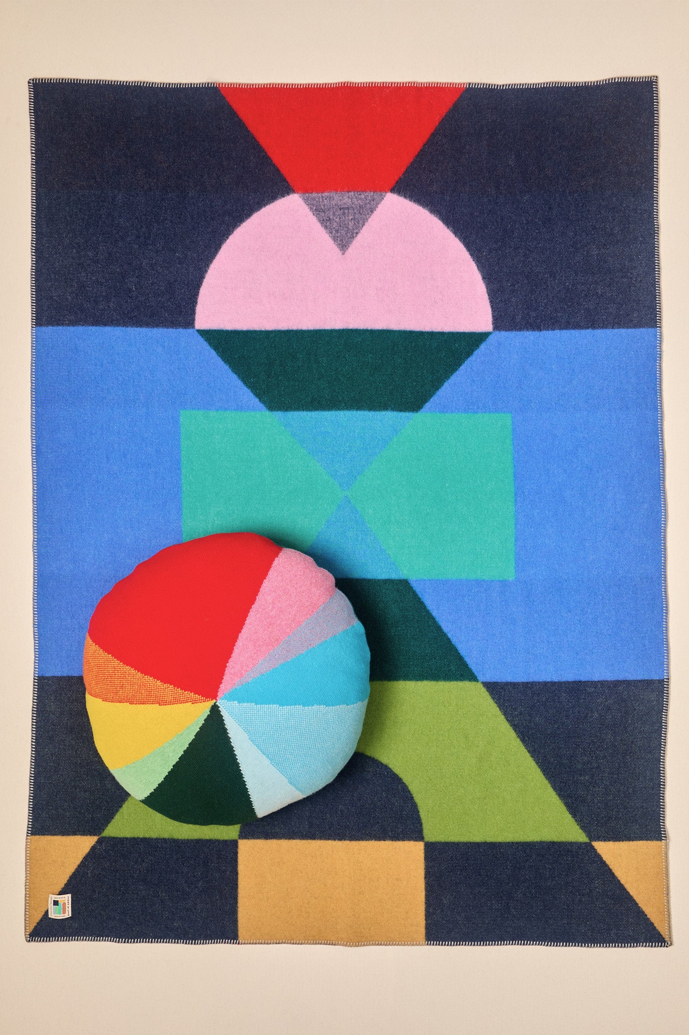 Colorful geometric patterned rug with a circular pillow on a beige background